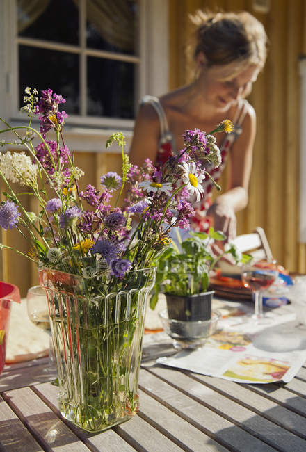 Букет з польових квітів з жінкою на фоні — стокове фото