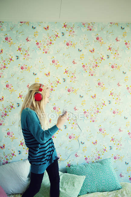 Mädchen hört Musik mit roten Kopfhörern im Zimmer — Stockfoto