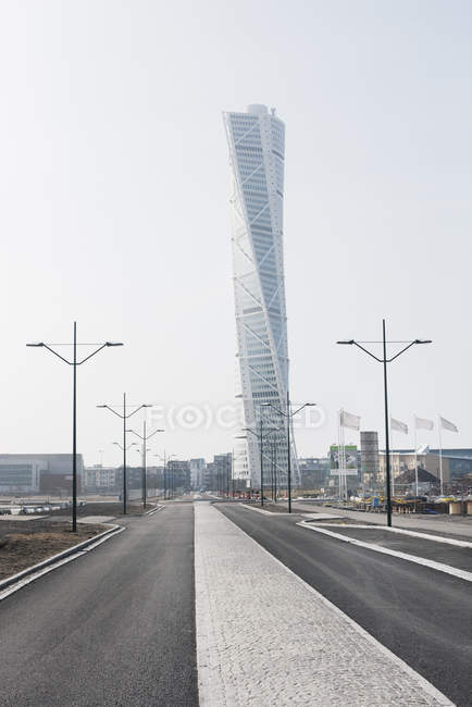 Вид на дорогу и современный небоскреб, окруженный зданиями — стоковое фото