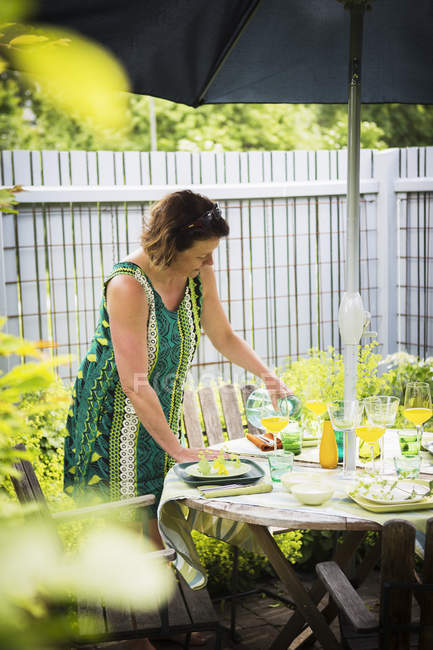 Женщина накрывает стол в саду, дифференциальный фокус — стоковое фото