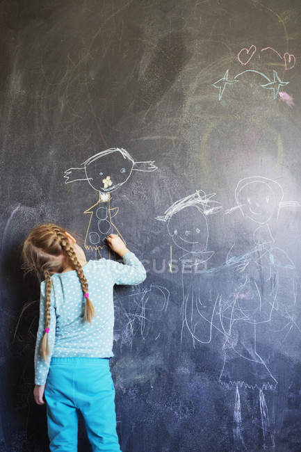Girl drawing on chalkboard, rear view — Stock Photo