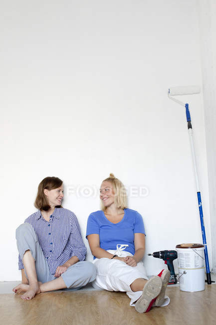 Young women resting by wall after home renovation work — Stock Photo
