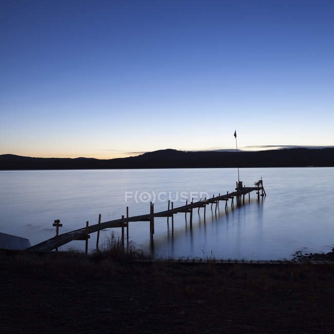 Long exposure shot of pier on lake at dusk — Stock Photo