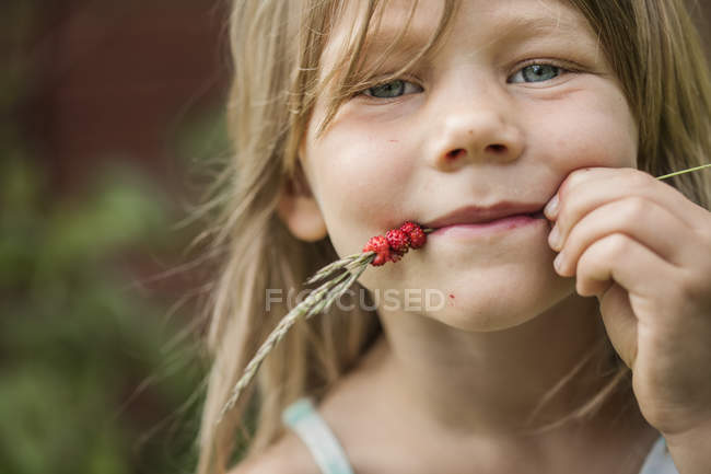 Retrato de menina com morangos selvagens em espigueta na boca — Fotografia de Stock