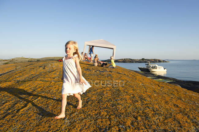 Familia descansando en la playa, chica caminando, enfoque en primer plano - foto de stock