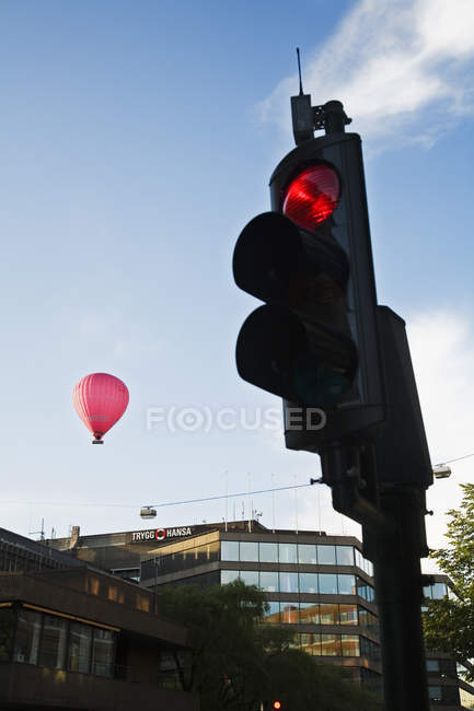 Cityscape with traffic lights on foreground and hot air balloon in background — Stock Photo
