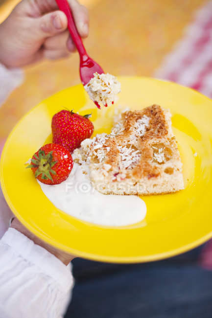 Petite fille mains tenant plaque de gâteau éponge aux fraises et fourchette — Photo de stock