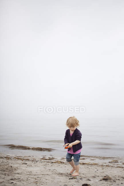 Chica jugando con arena en la playa, enfoque selectivo - foto de stock