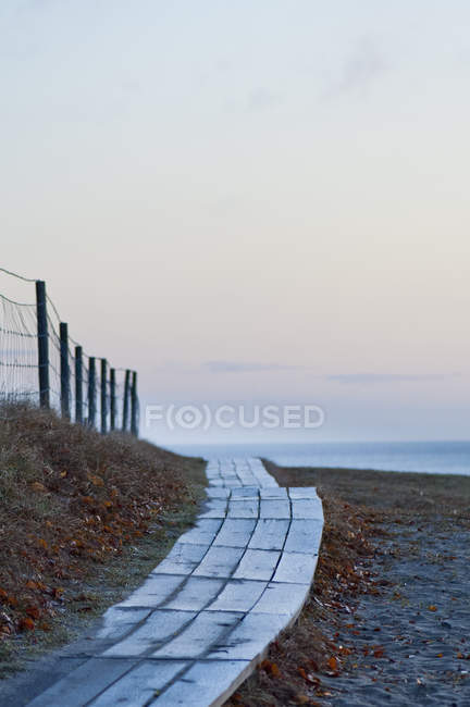 Lungomare in legno che conduce alla spiaggia al tramonto — Foto stock