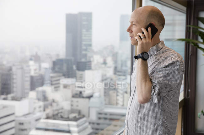 Homem falando no telefone e olhando através da janela — Fotografia de Stock