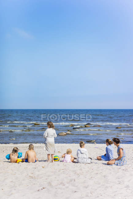 Vista posteriore di due donne con bambini sulla spiaggia — Foto stock