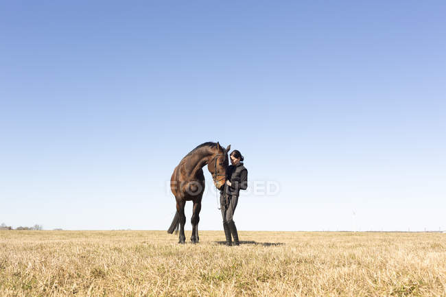 Mulher de pé com cavalo marrom ao ar livre — Fotografia de Stock