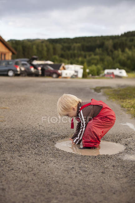 Хлопчик грає в калюжі, зосередьтеся на передньому плані — стокове фото