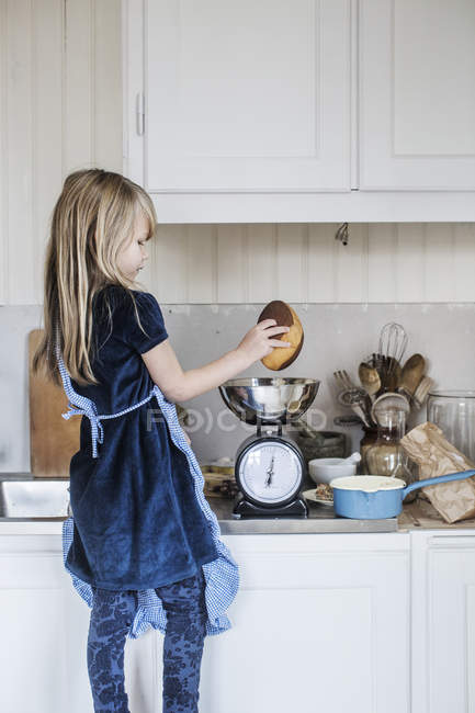 Bambina con i capelli biondi che cucina in cucina — Foto stock