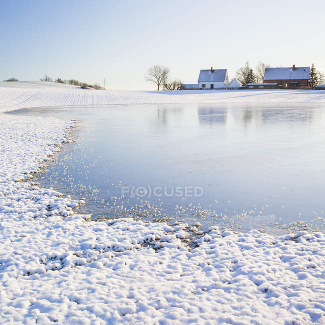 Houses reflecting in lake water in winter landscape — Stock Photo