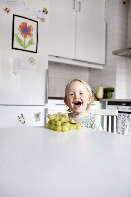 Мальчик смеется и смотрит в камеру на кухне — стоковое фото