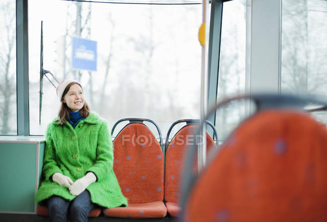 Jovem mulher sentada em bonde e sorrindo — Fotografia de Stock