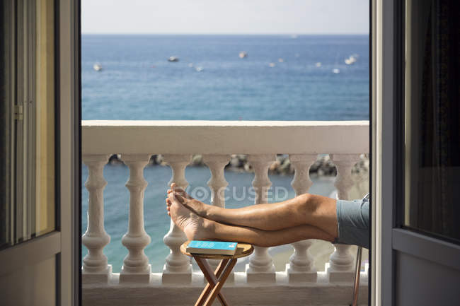 Чоловік відпочиває на балконі біля моря, вибірковий фокус — стокове фото