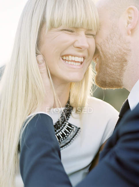 Groom kissing bride cheek, focus on foreground — Stock Photo