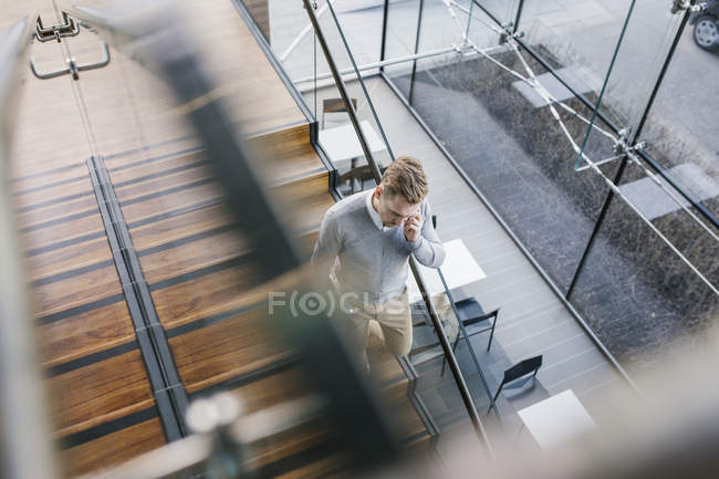 Молодой бизнесмен спускается вниз и разговаривает по телефону — стоковое фото