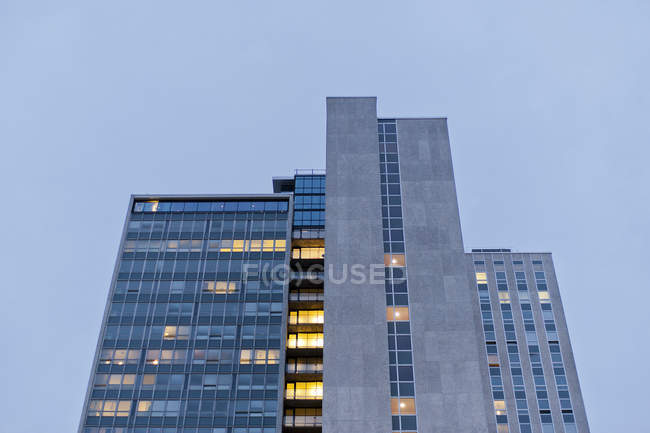 Vista de ángulo bajo del edificio con ventanas iluminadas al atardecer - foto de stock