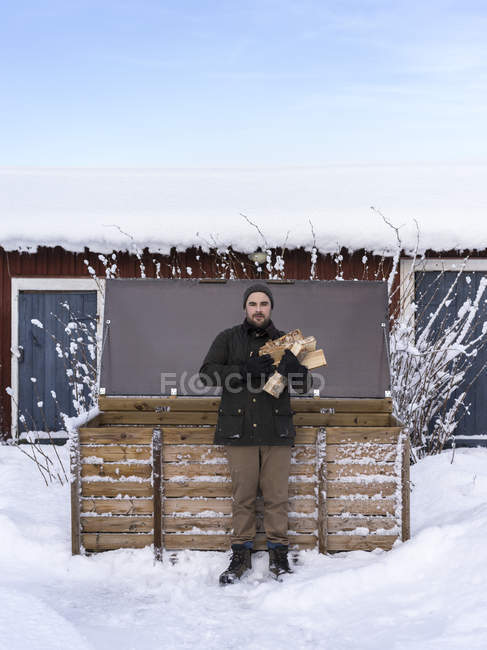 Homem segurando lenha por caixa de armazenamento — Fotografia de Stock