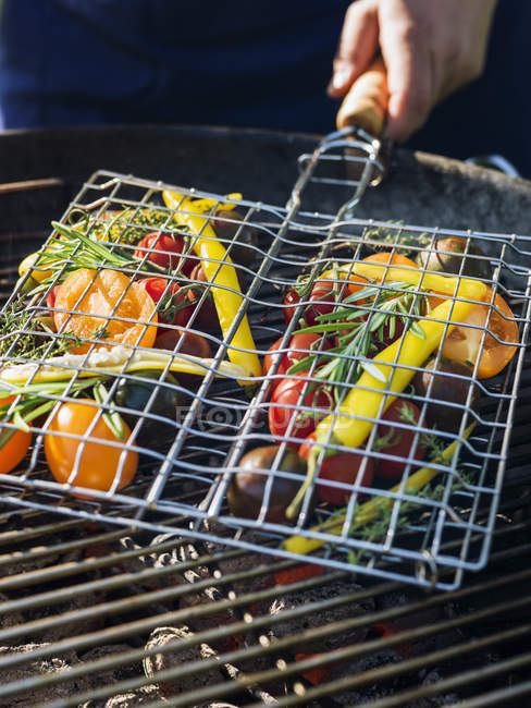 Mão segurando legumes grelhados na churrasqueira — Fotografia de Stock