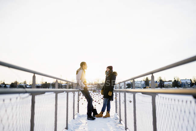 Молода пара стоїть обличчям до обличчя на пішохідному мосту, вибірковий фокус — стокове фото
