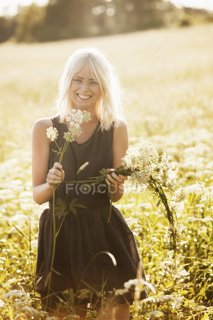 Jeune femme avec un tas de fleurs sauvages — Photo de stock