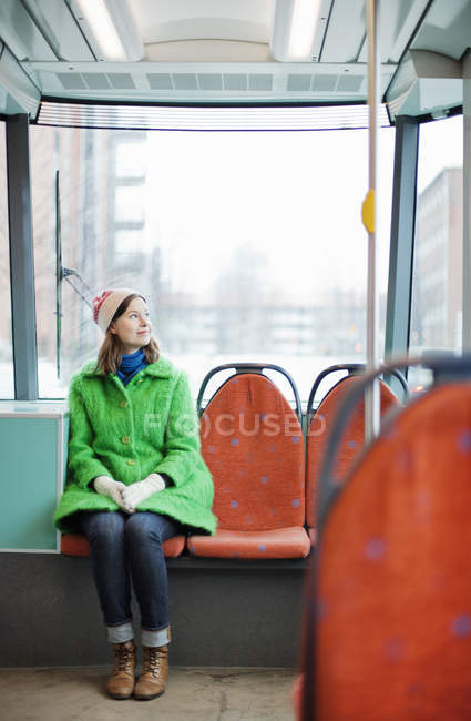 Giovane donna vestita con cappotto verde seduta in tram — Foto stock