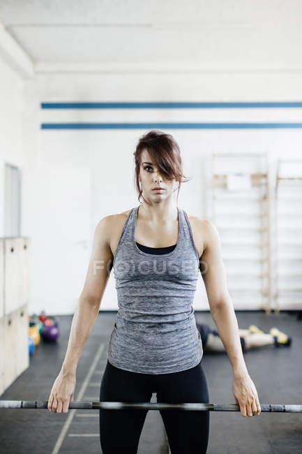 Молодая женщина тренируется с штангой в тренажерном зале — стоковое фото
