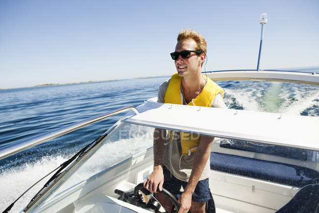 Young man driving speedboat at summer — Stock Photo