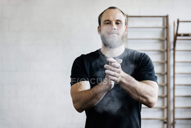 Bärtiger Mann kreidet Hände in Turnhalle — Stockfoto