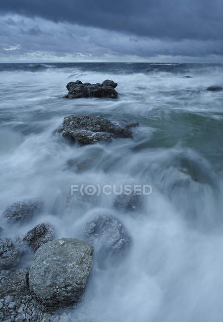 Ciel couvert au-dessus du rivage rocheux avec vagues floues — Photo de stock