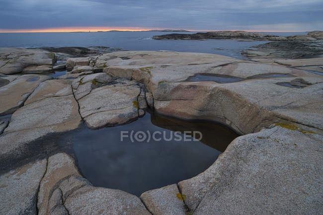 Costa rocciosa e cielo nuvoloso al tramonto — Foto stock