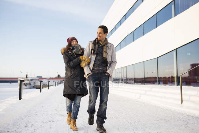 Junges Paar spaziert im Winter am Flussufer entlang und konzentriert sich auf den Vordergrund — Stockfoto