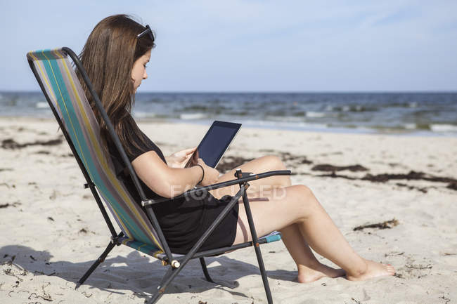 Ragazza adolescente utilizzando tablet digitale sulla spiaggia — Foto stock