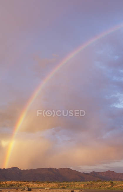 Arco-íris sobre a cordilheira ao pôr do sol — Fotografia de Stock