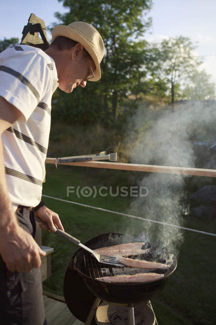 Reifer Mann grillt Fisch, selektiver Fokus — Stockfoto
