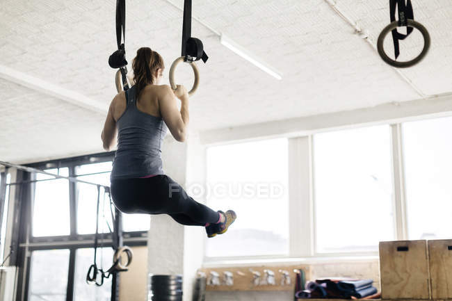 Вид ззаду на молоду жінку, що тренується на гімнастичних кільцях — стокове фото