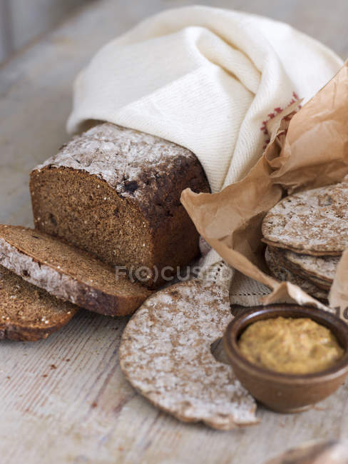 Pan de centeno en toalla de té y pan crujiente en bolsa de papel con aderezo - foto de stock