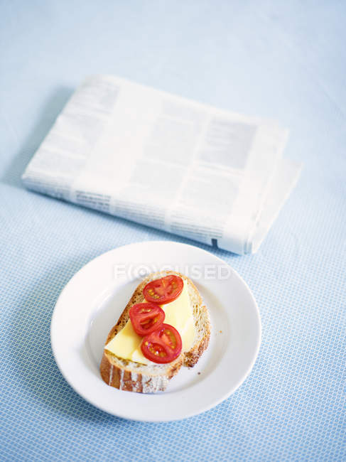 Piatto con panino e giornale su tovaglia blu — Foto stock