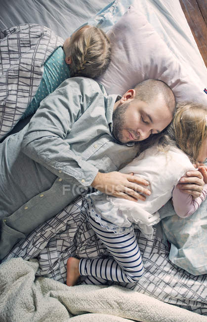Father sleeping with daughters on bed — Stock Photo