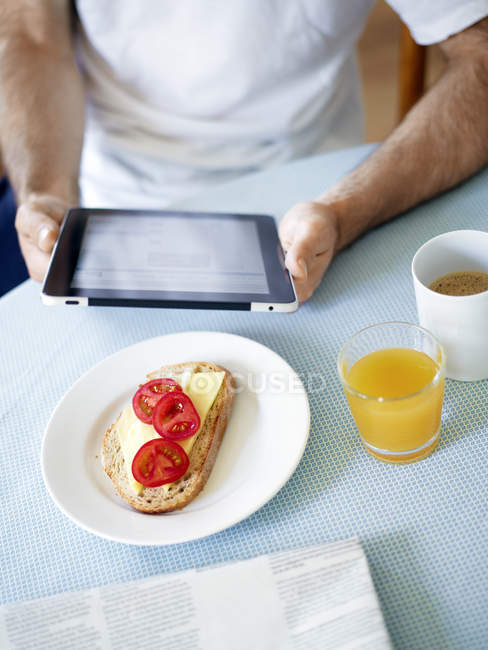 Mid section of man using tablet pc at breakfast table — Stock Photo
