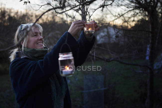 Mature woman decorating tree with tealights — Stock Photo