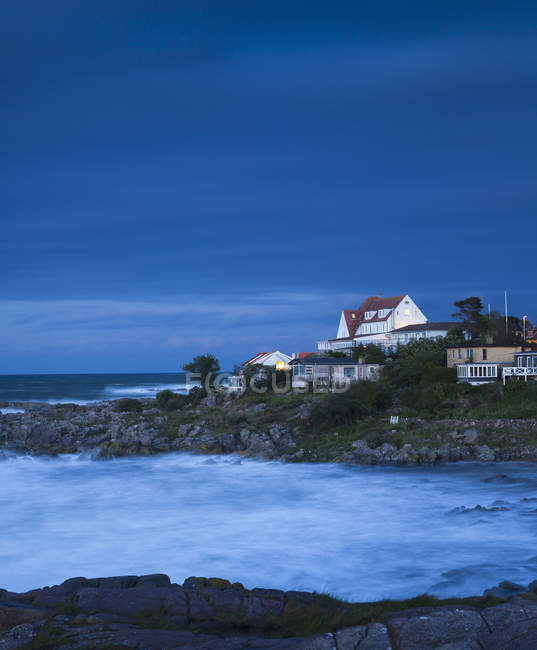 Casas en la costa con olas de surf al atardecer - foto de stock