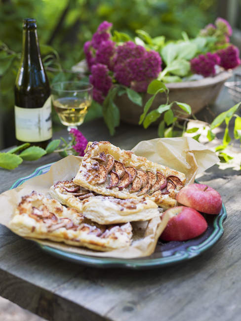Apple pies and fresh apple halves on plate — Stock Photo