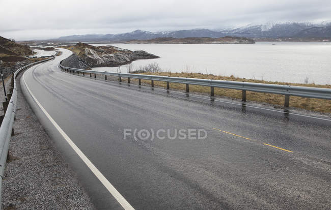 Winding coastal road with snowcapped mountains view — Stock Photo