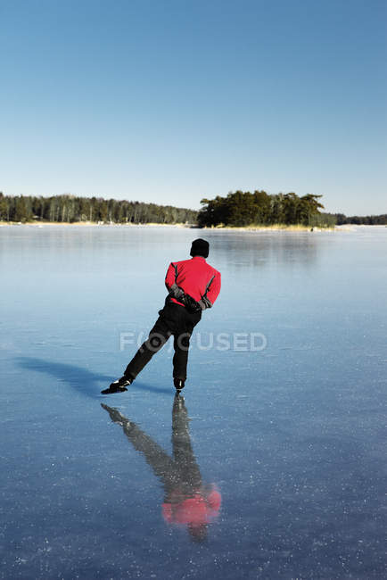 Rear view of man ice-skating on frozen lake — Stock Photo