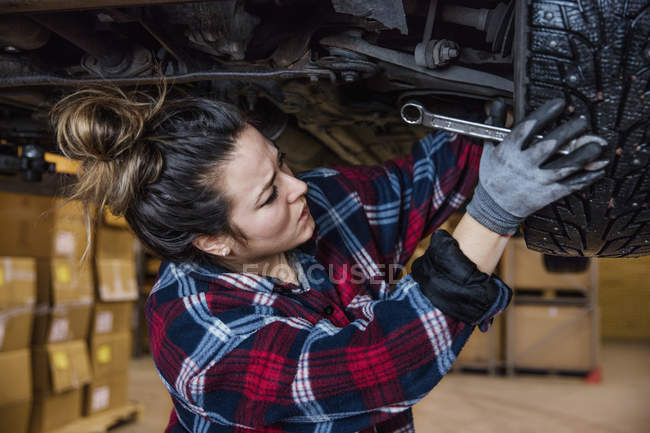 Mecánica femenina con camisa a cuadros ajustando la rueda - foto de stock